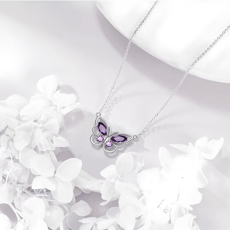 Origsoul delicate butterfly necklace with purple gemstone wings on silver chain surrounded by white flowers