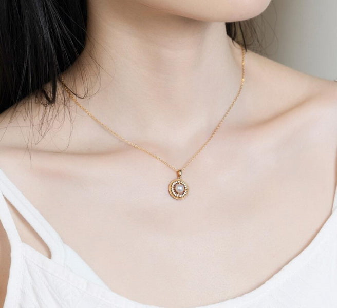 Origsoul freshwater pearl necklace with gold chain and circular pendant worn on model's neck