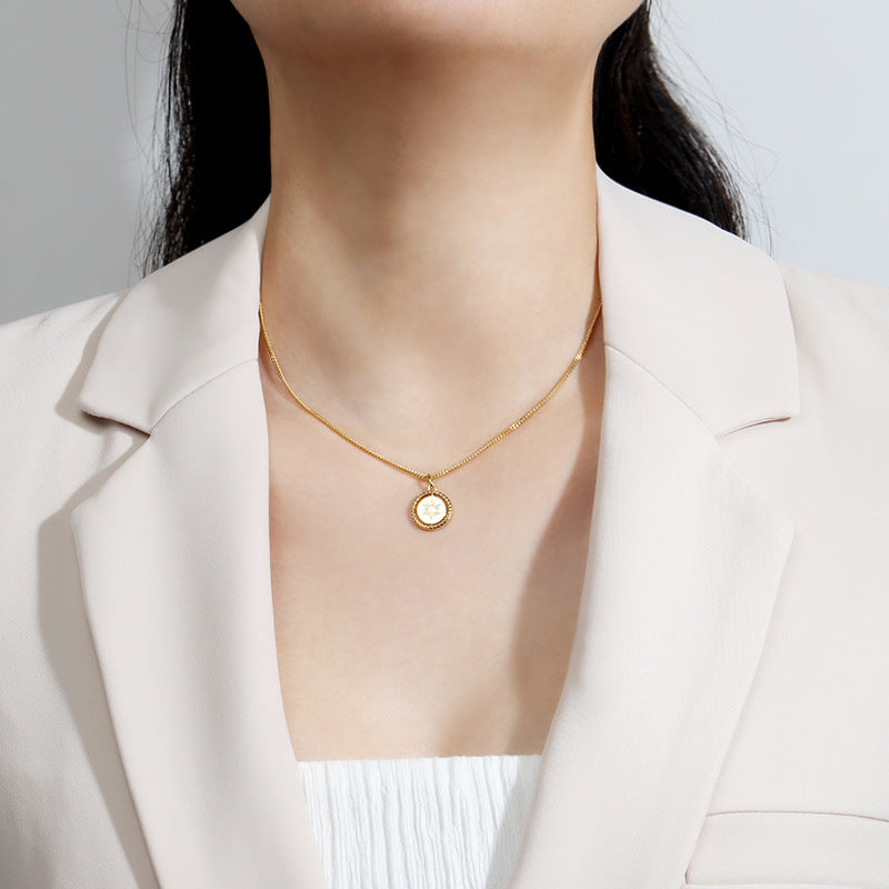 Gold sun charm jewelry necklace from Origsoul worn with white top and beige blazer