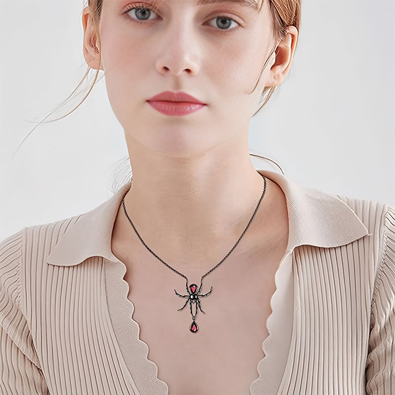 Origsoul gothic spider necklace with red gem accents worn by woman with beige pleated top
