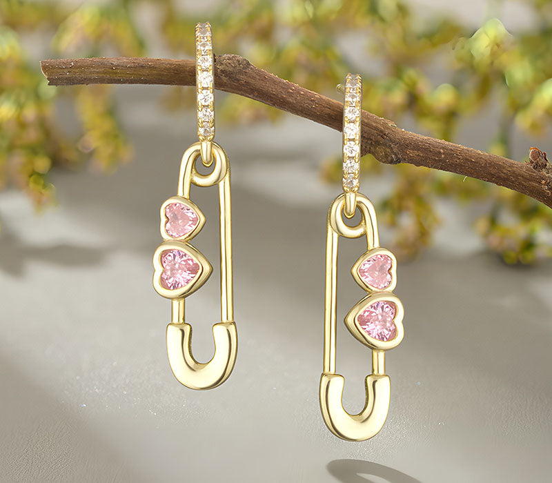 Origsoul heart shaped safety pin earrings with gold-tone and pink heart gemstones hanging on branch