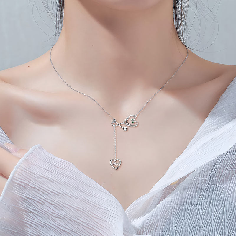 Origsoul infinity heart stethoscope necklace in silver worn on a woman with a white textured top