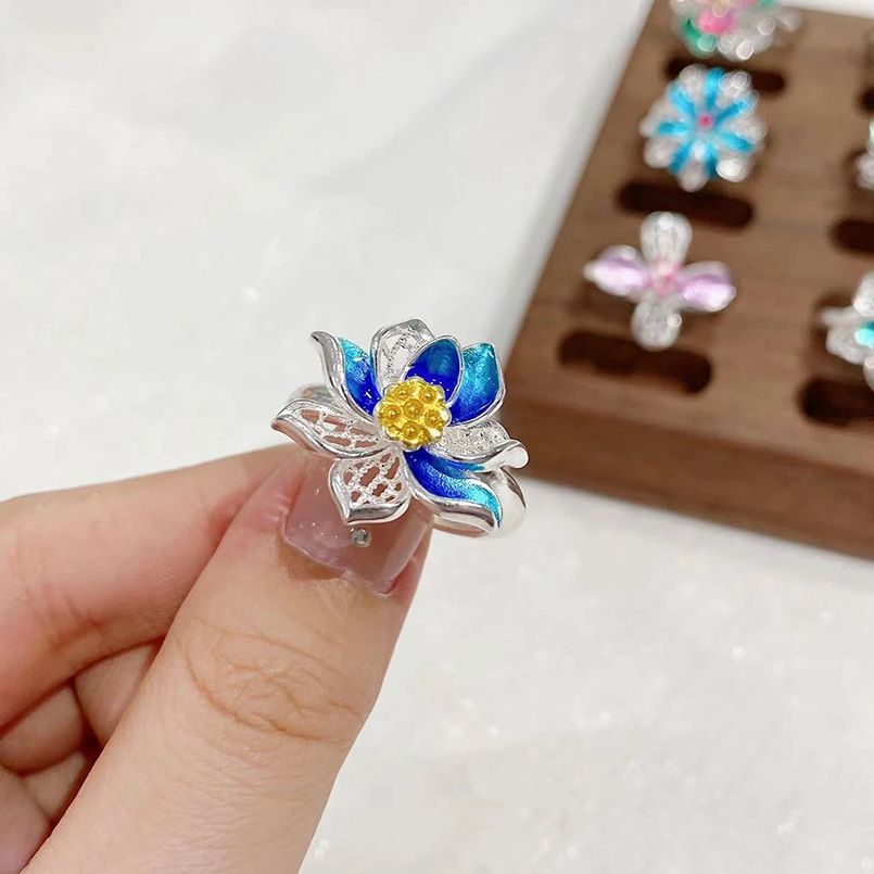Origsoul March birth flower ring with blue petals and yellow center held between fingers