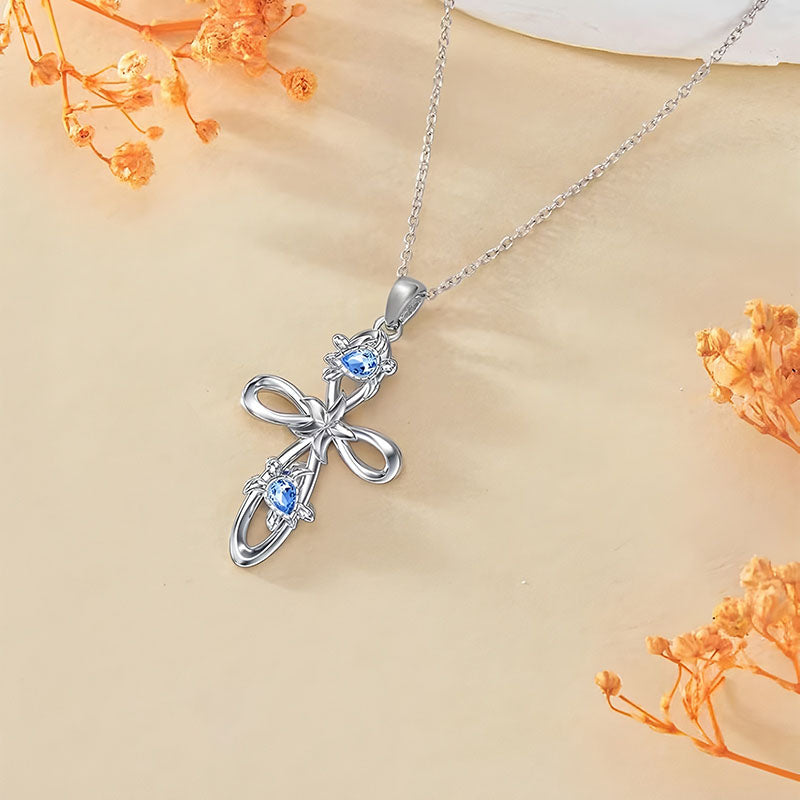 Origsoul ocean cross pendant necklace with silver chain and blue gemstone accents on a beige background