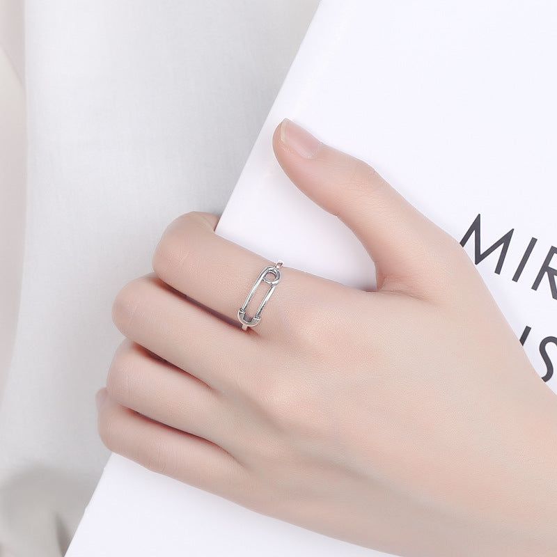 Origsoul silver safety pin ring worn on a hand holding a white book