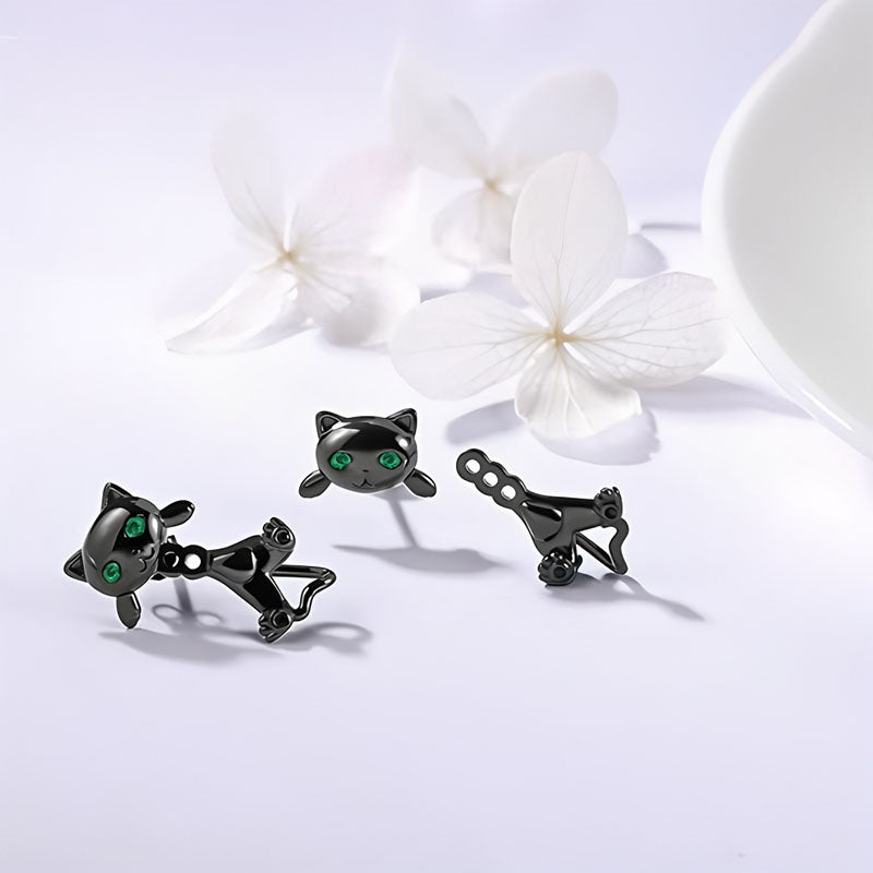 Origsoul black cat face earrings with green eyes displayed on white surface with white flowers