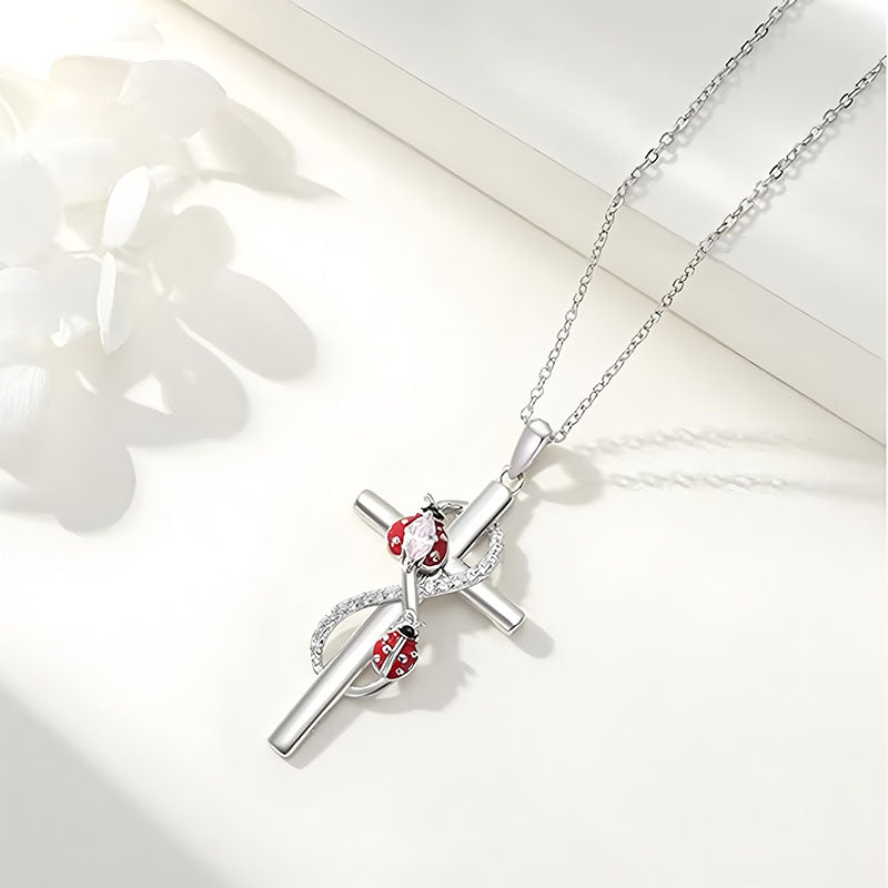 Sterling silver cross ladybug necklace with intricate details and a shiny finish