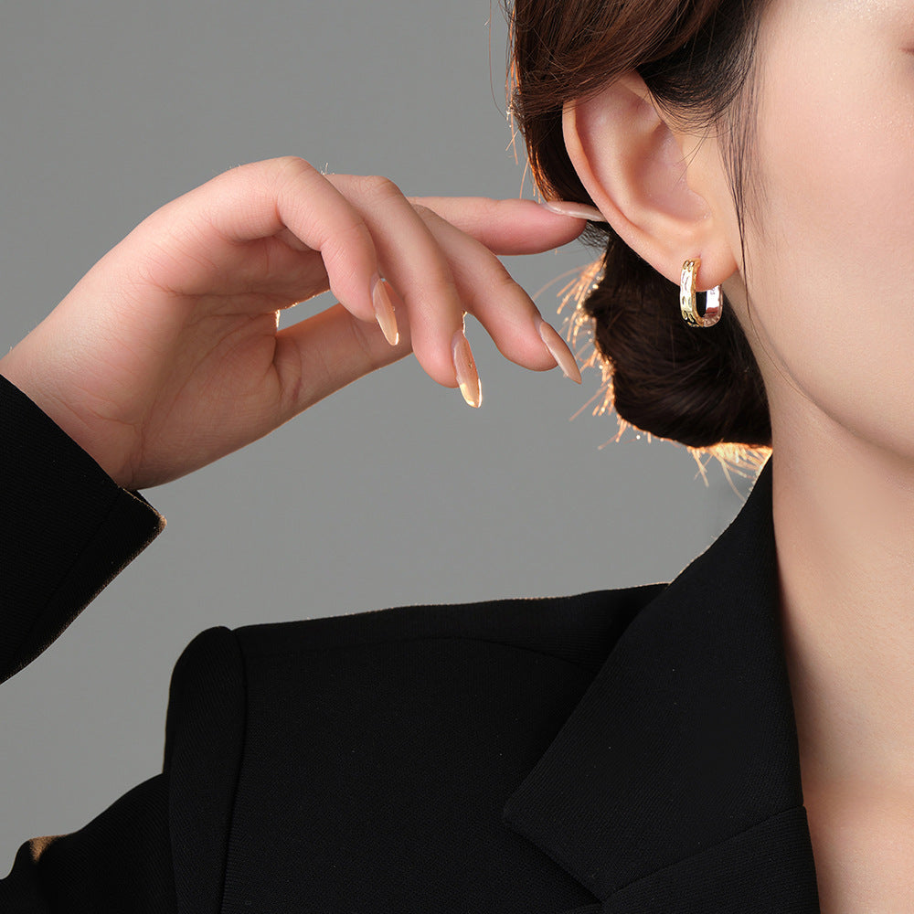 Origsoul unique gold hoop earrings worn by woman with black blazer on gray background