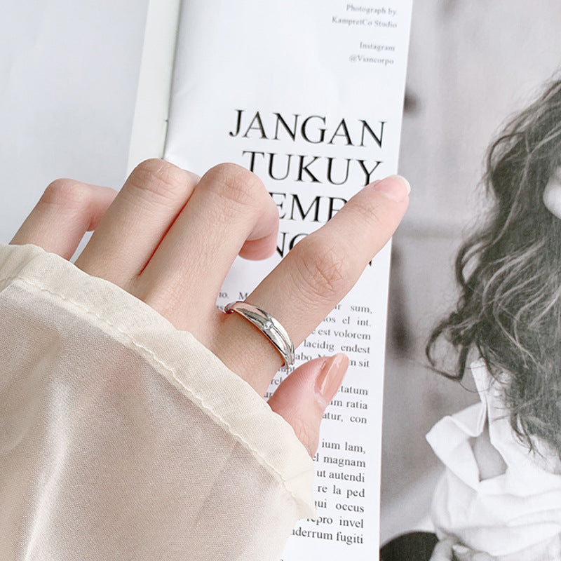 Unique promise ring for him and her worn on finger with a soft beige sleeve and magazine background