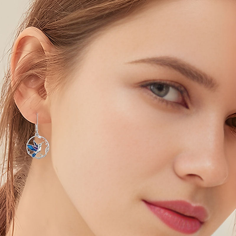 Origsoul handcrafted bird drop earrings worn by woman with delicate silver and blue design