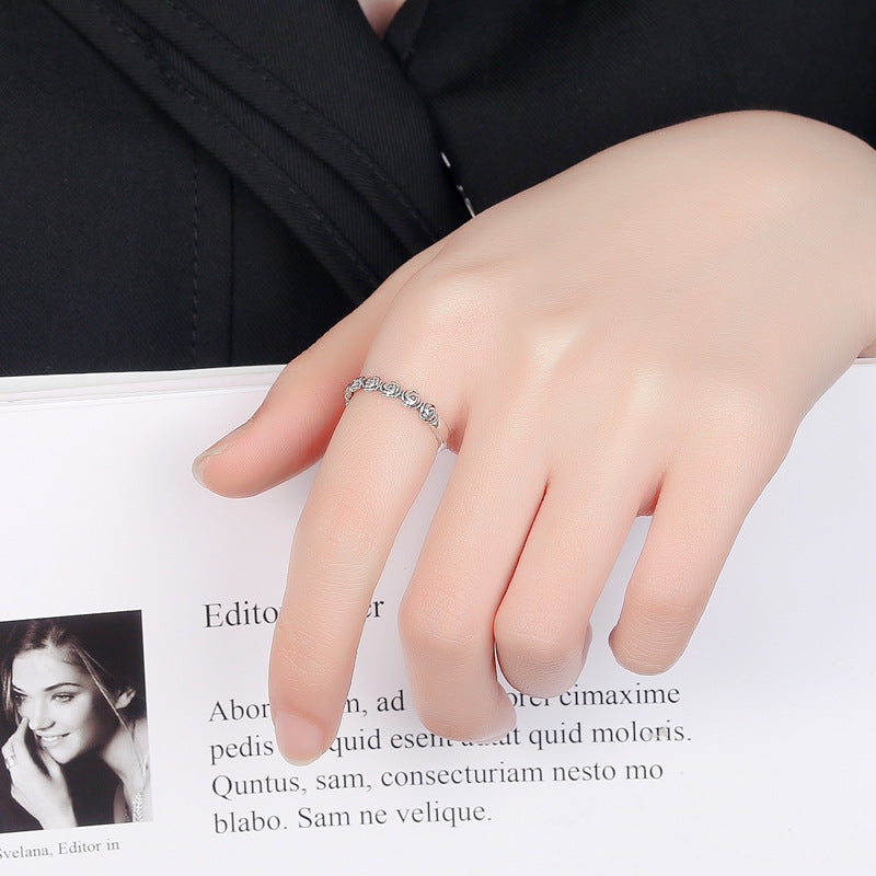 Elegant silver premium rings for women displayed on a hand over a magazine page with black clothing background