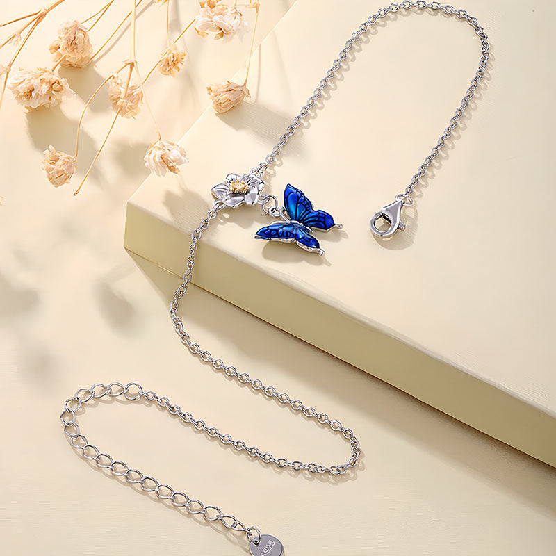 Origsoul blue butterfly bracelet with silver chain and floral design on beige background