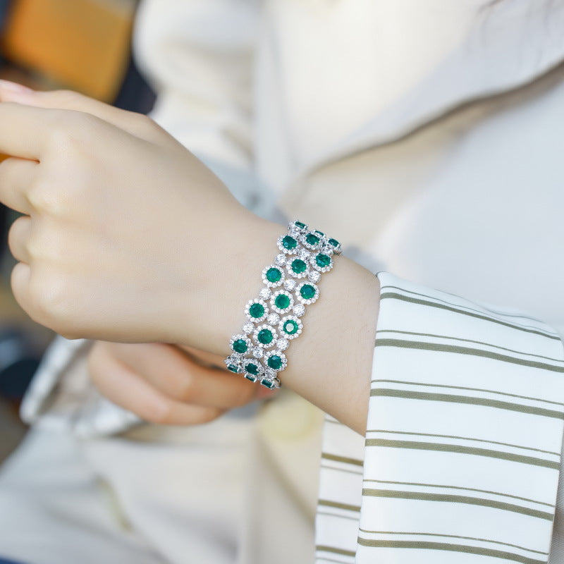 Origsoul bracelet tennis diamond with green gemstones worn on wrist complementing white striped sleeve