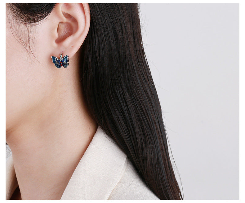 Origsoul butterfly earrings for women in blue worn on ear with dark hair and white top