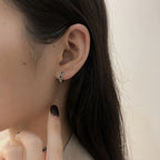 Origsoul cosmic twisted style earrings for women worn on ear with dark hair and neutral background