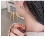 Origsoul daisy hoop earrings for women worn on ear with close-up of silver textured design