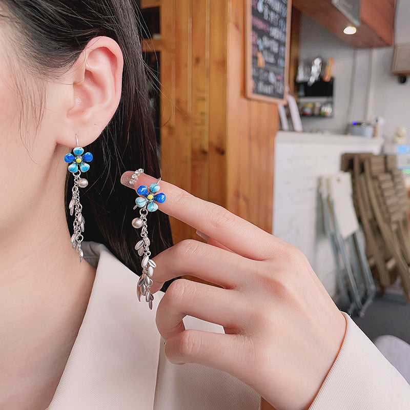 Origsoul daisy tassel earrings with blue flower and silver dangling chains worn by woman