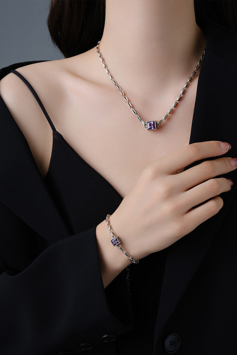 Origsoul designer embossed chain bracelet with purple gemstone worn with matching necklace and black outfit