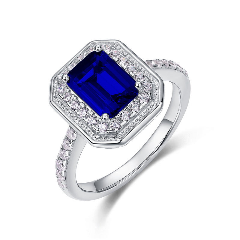 Origsoul emerald cut-engagement ring with a deep blue center stone and diamond halo on silver band