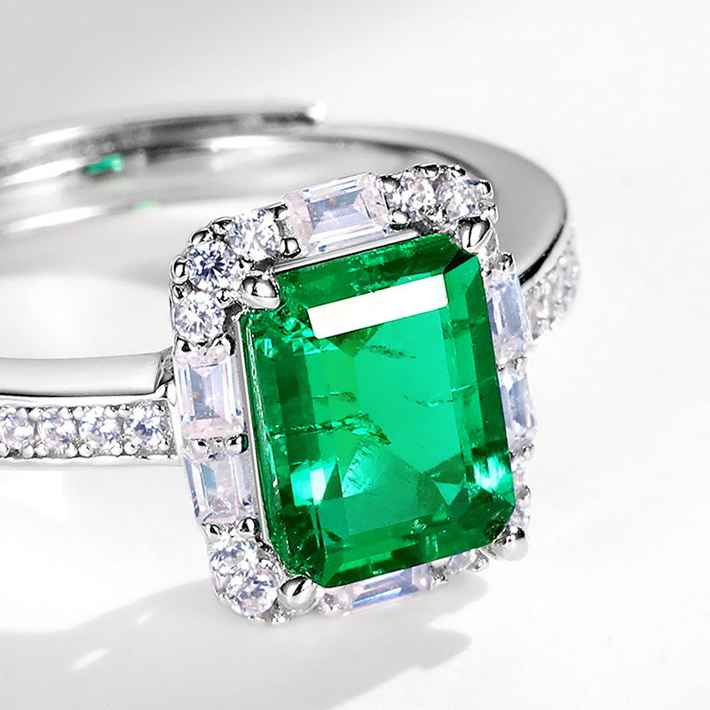 Origsoul emerald cut-engagement ring with vibrant green center stone and surrounding diamonds on silver band
