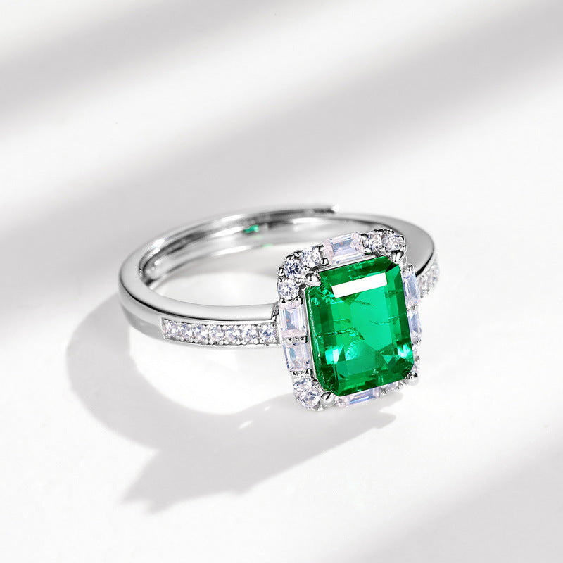 Origsoul emerald cut-engagement ring with a large green center stone and diamond accents on a silver band