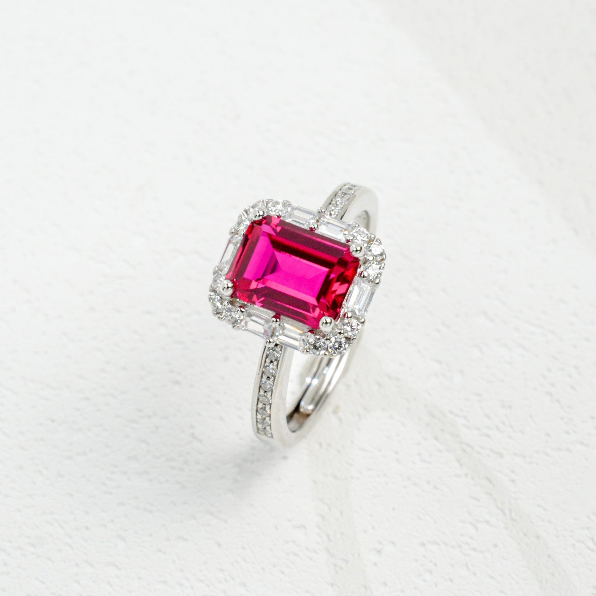 Origsoul emerald cut-engagement ring with a vibrant pink center stone and diamond halo on silver band