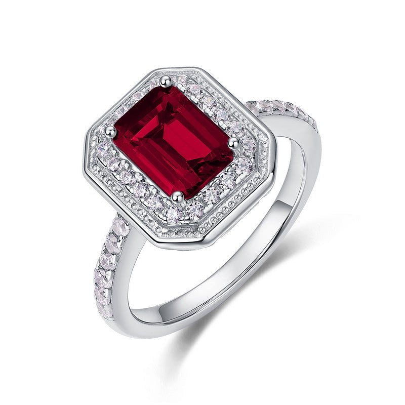 Origsoul emerald cut-engagement ring featuring a red center stone surrounded by small diamonds on silver band