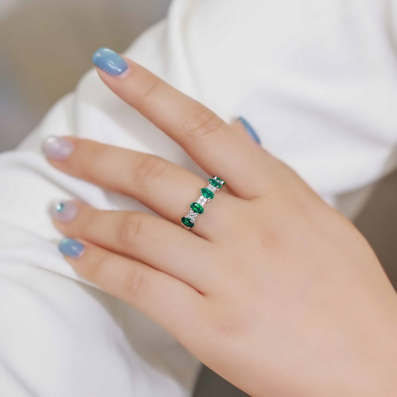 Origsoul emerald engagement ring cut with multiple emerald stones on hand with blue nails