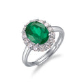 Origsoul engagement ring emerald cut featuring a large green gemstone surrounded by smaller clear stones on a silver band