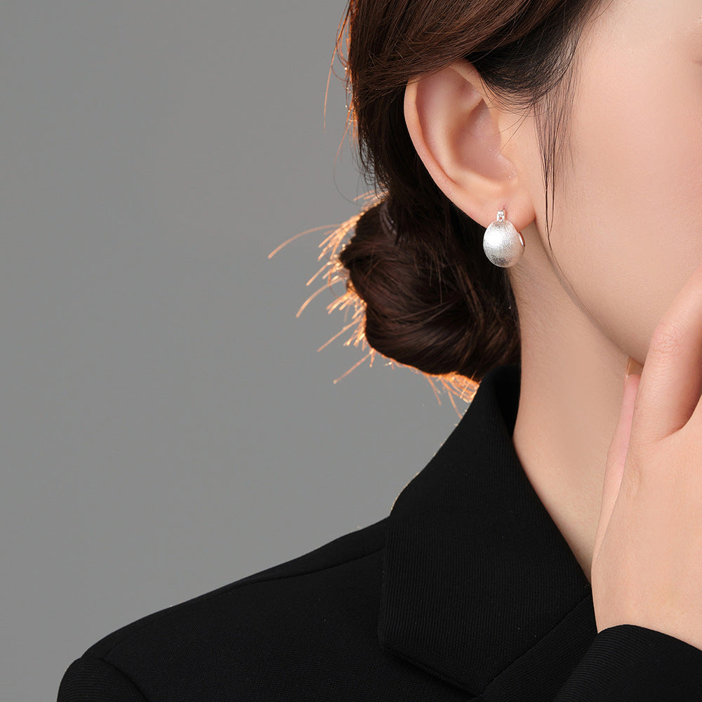 Origsoul hand-drawn silver earrings worn by woman in black outfit with elegant hairstyle