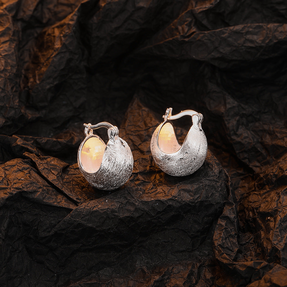 Origsoul hand-drawn silver earrings with textured design on black crinkled background