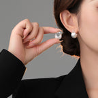 Origsoul hand-drawn silver earrings worn and held by a woman with elegant black outfit