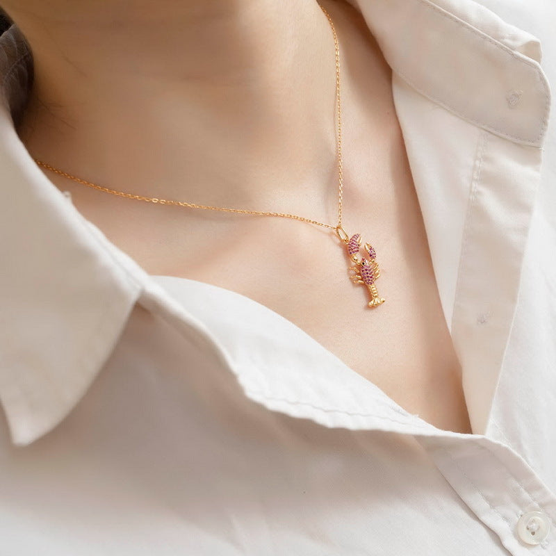Origsoul lobster pendant necklace in gold tone showcasing sterling silver jewlry on a white shirt