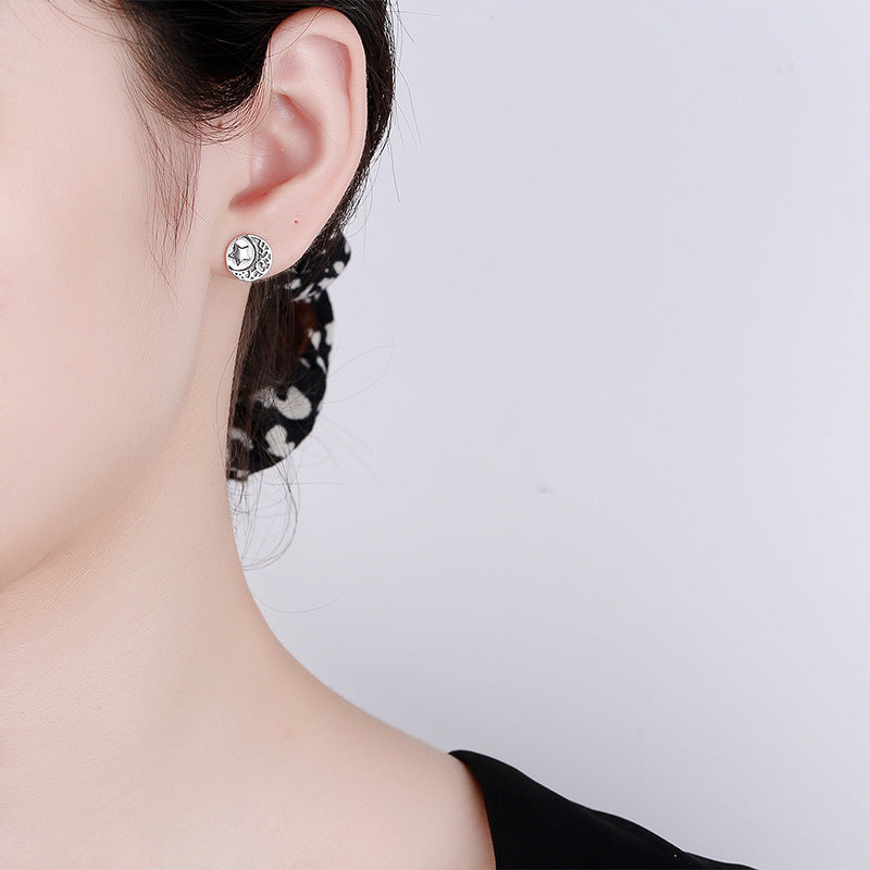 Origsoul cosmic sun and moon stud earrings worn on ear with detailed celestial design