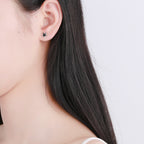 Cosmic jewelry nautical star stud earrings worn on ear with long black hair background