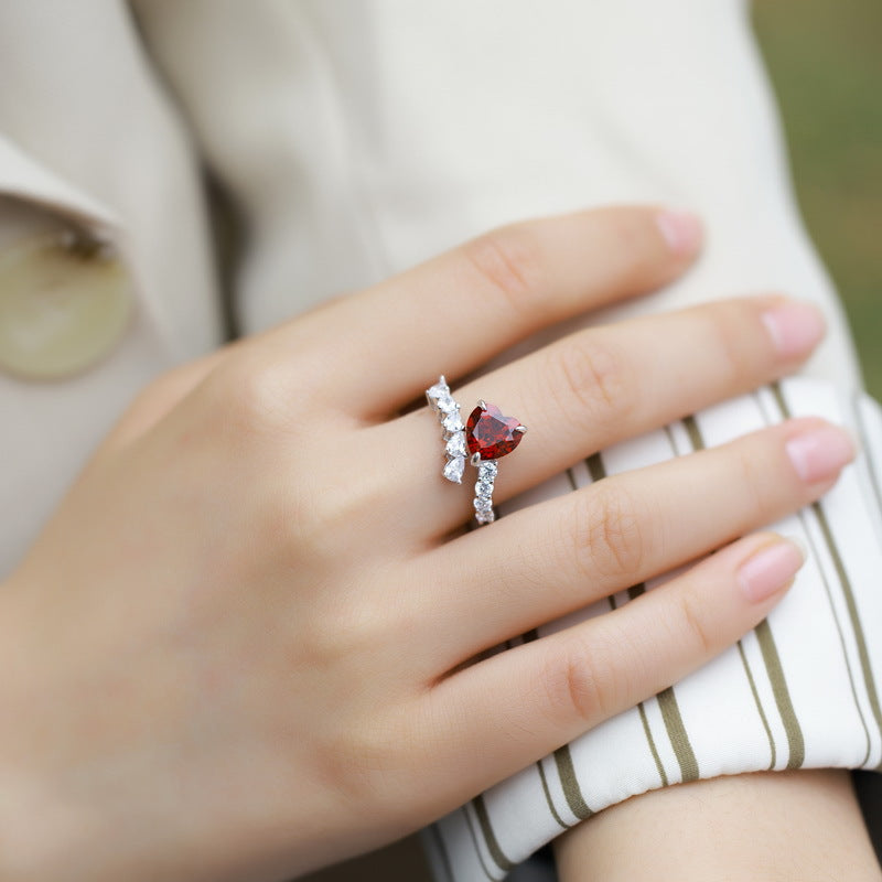 Origsoul emerald cut-engagement ring with a red heart-shaped center stone and diamond accents on hand
