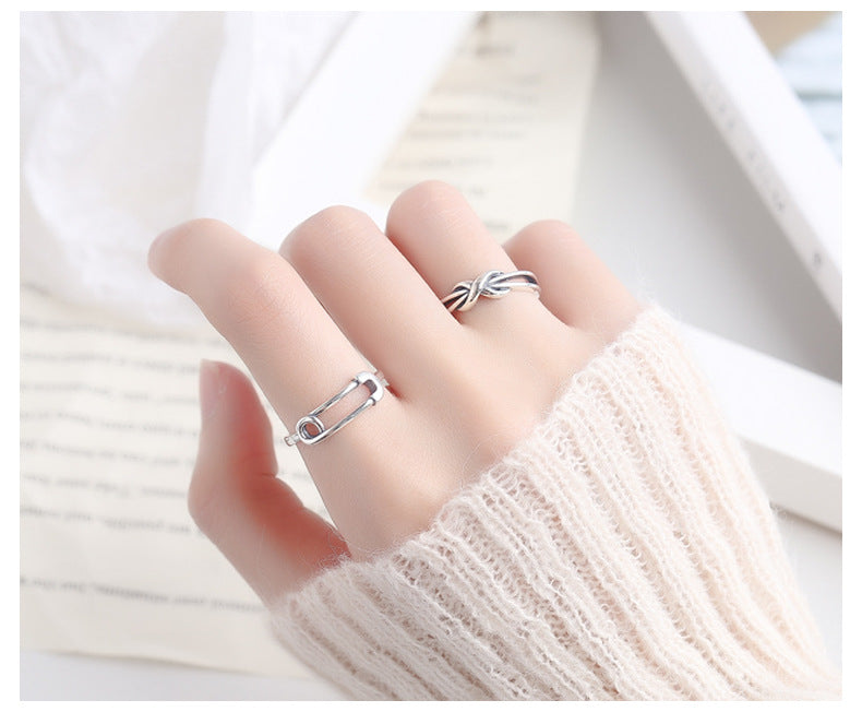 Origsoul silver safety pin ring worn on finger with another silver twisted ring and cream knit sweater