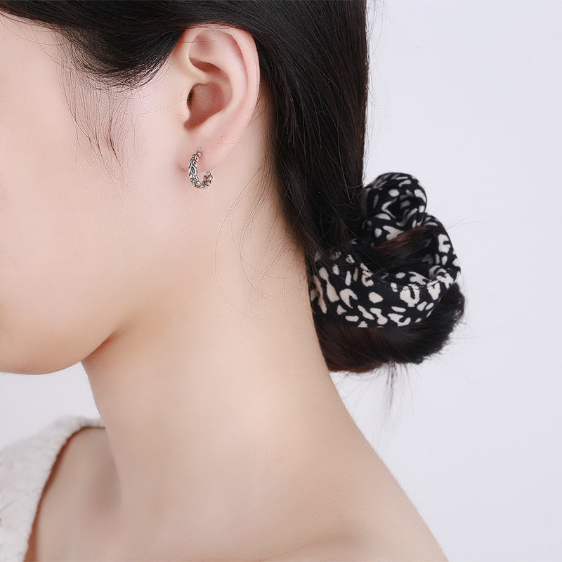Origsoul silver wheat hoop earrings worn by woman with hair tied back in black patterned scrunchie
