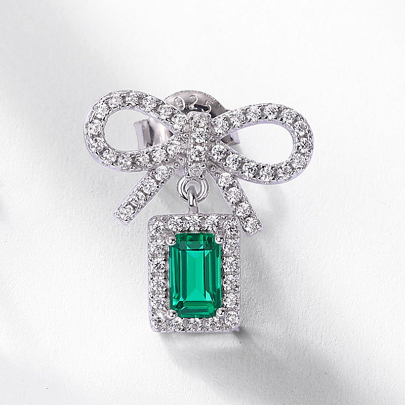 Origsoul silver sterling silver earrings featuring a bow design with sparkling clear stones and a green rectangular gem