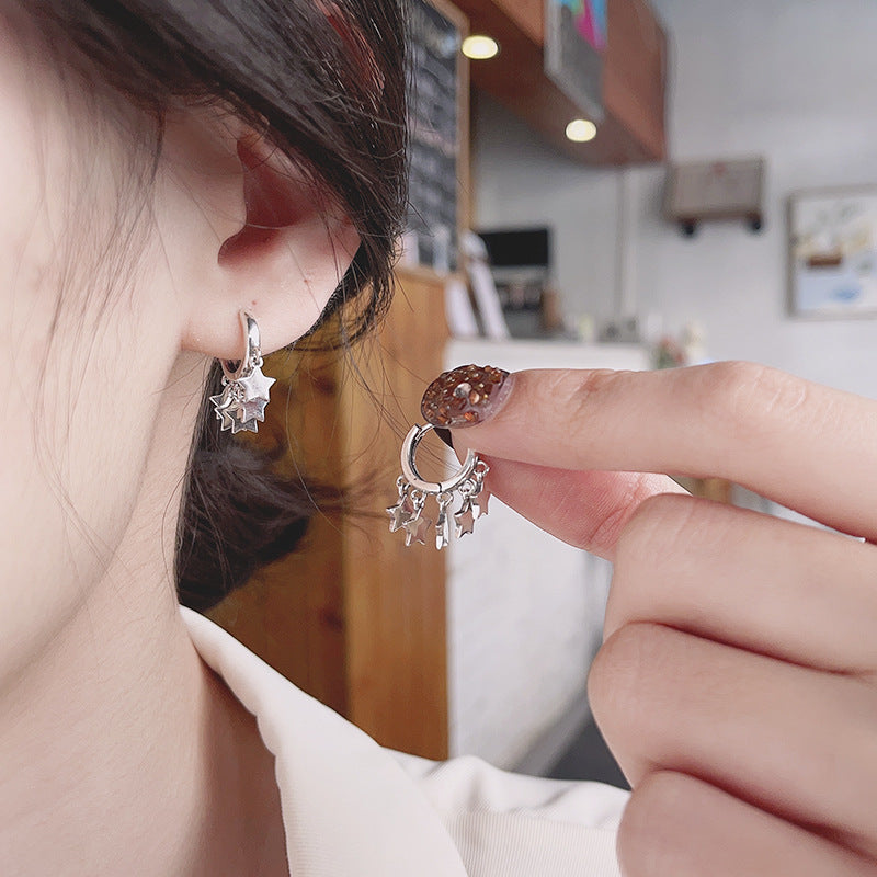 Origsoul star tassel hoop earrings worn and held near ear showing silver cosmic jewelry design