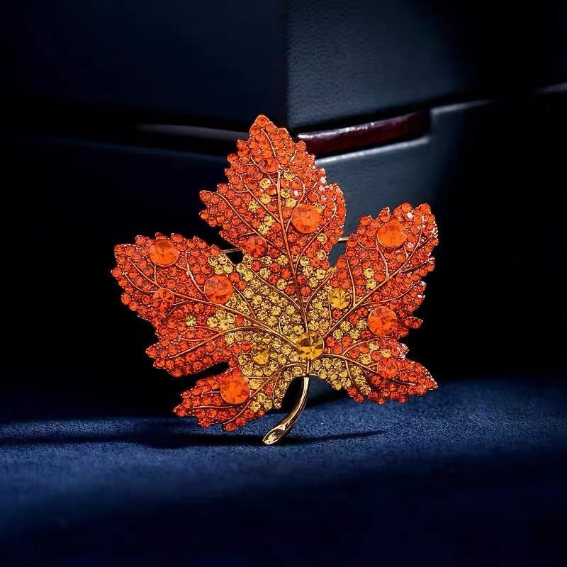Origsoul brooch featuring a sparkling orange and yellow Toronto maple leaf design with gemstone accents