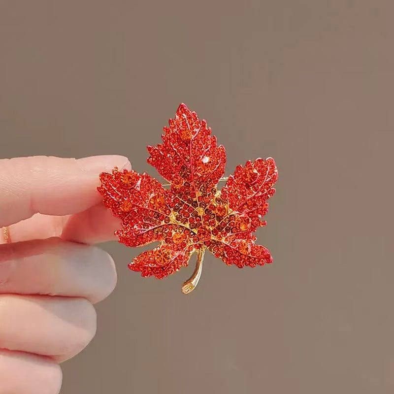 Origsoul red crystal Toronto maple leaf brooch held between fingers with detailed design