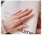 Unique minimalist silver ring with a small red bead worn on hand with French manicure nails