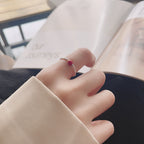 Origsoul unique minimalist silver ring with small red bead worn on finger against blurred background
