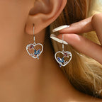 Origsoul hummingbird heart earrings with blue bird and red flower details worn on ear