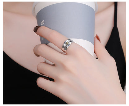 Close-up of hand wearing Origsoul sun ray ring silver holding a gray and white cup