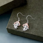 Origsoul whimsical mushroom charm earrings with silver and rose gold tones on textured surface